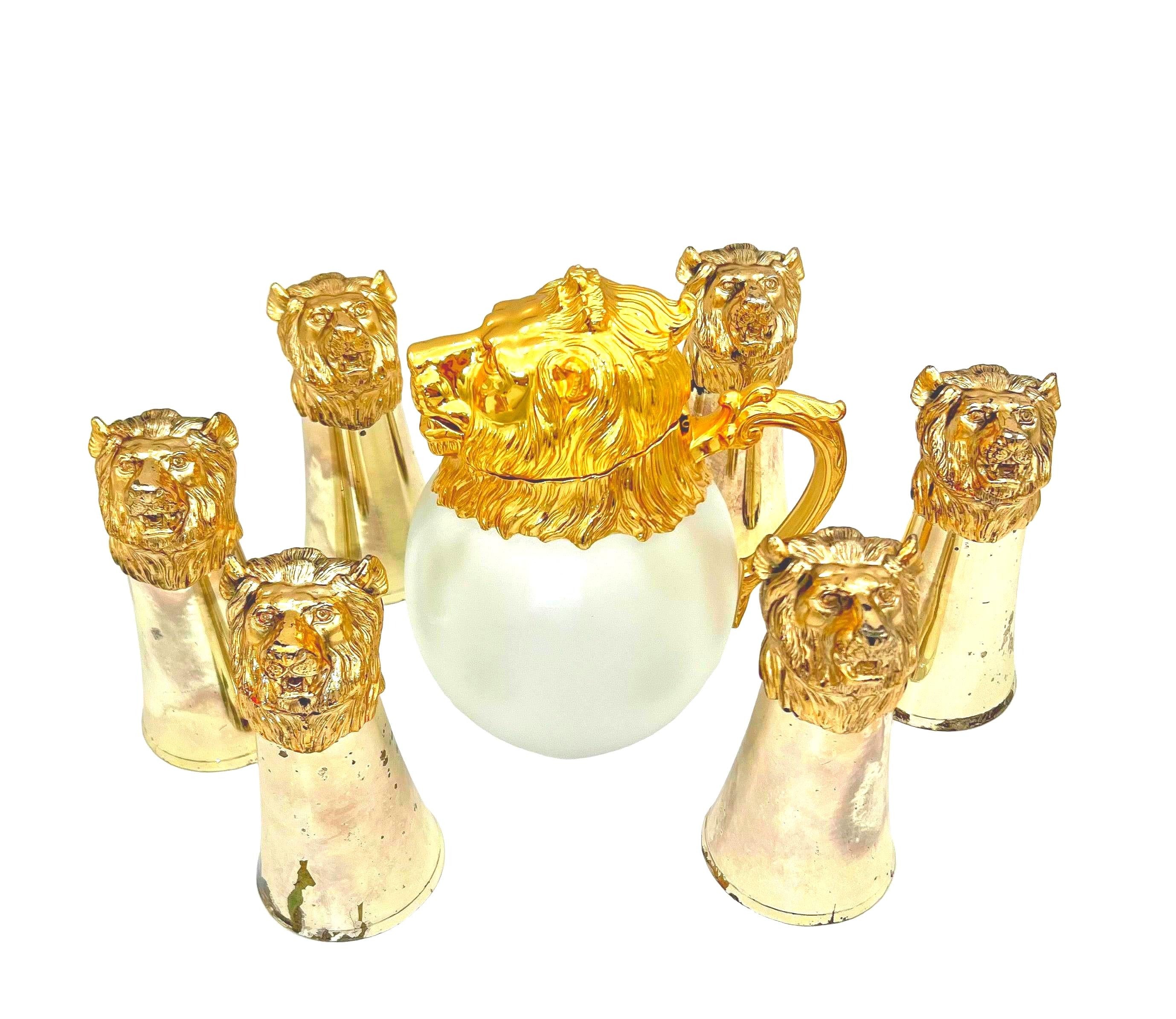 Rare set of 7 Carole Stupell mid-century barware featuring a glass pitcher and stirrup cups with silver-toned lion head bases.