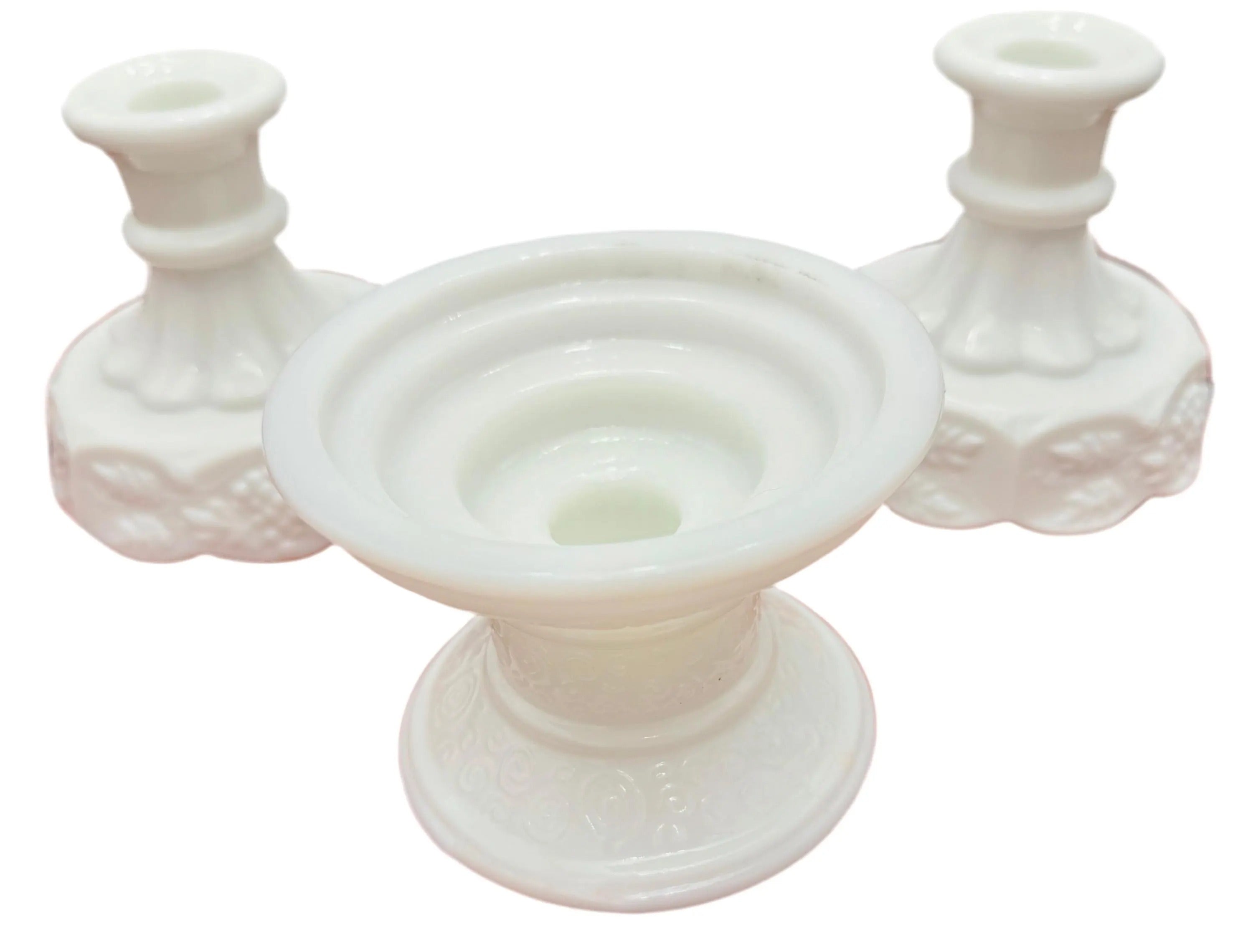 A curated trio of vintage milk glass candle holders in varying heights and classic patterns.
