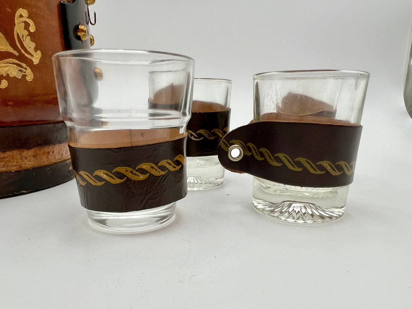 VINTAGE LEATHER WRAPPED WHISKY JUG WITH BRASS TAP AND4 LEATHER WRAPPED SHOT GLASSES