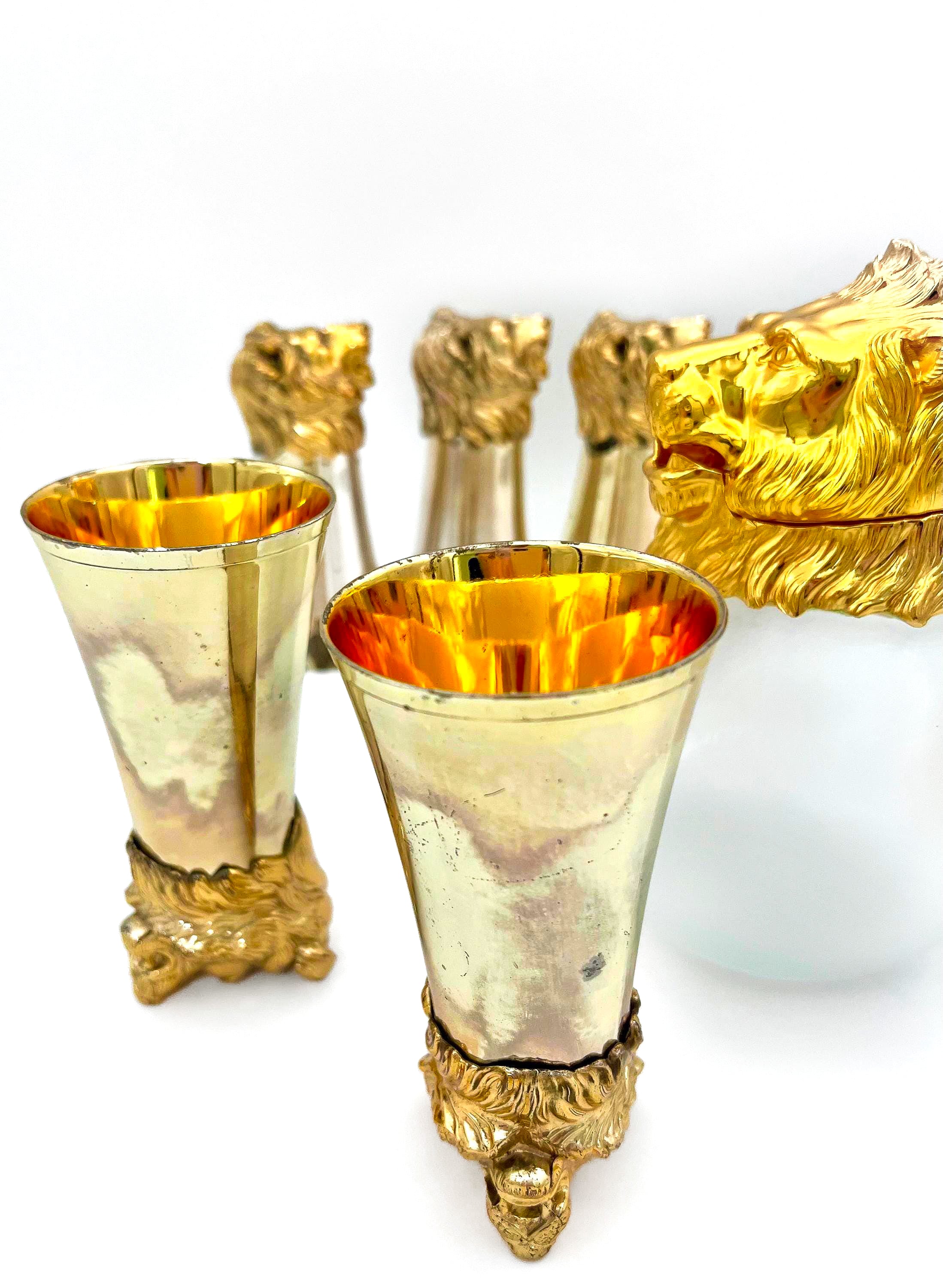 Rare set of 7 Carole Stupell mid-century barware featuring a glass pitcher and stirrup cups with silver-toned lion head bases.