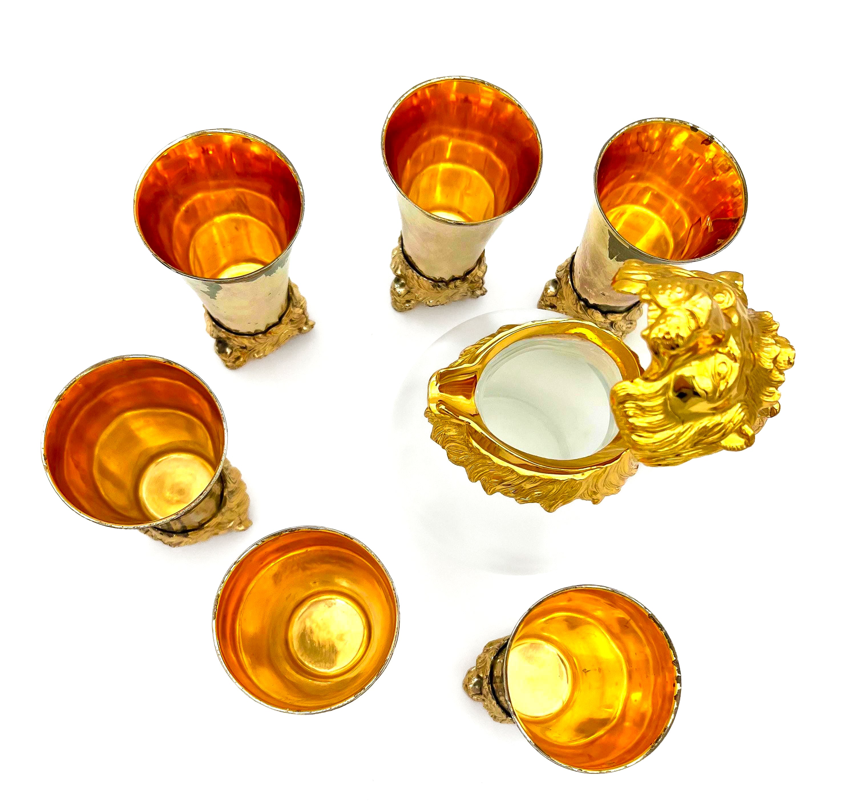 Rare set of 7 Carole Stupell mid-century barware featuring a glass pitcher and stirrup cups with silver-toned lion head bases.