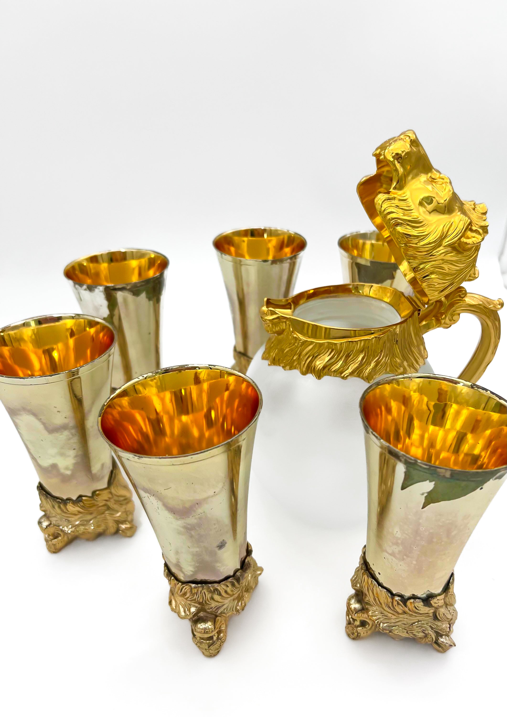 Rare set of 7 Carole Stupell mid-century barware featuring a glass pitcher and stirrup cups with silver-toned lion head bases.