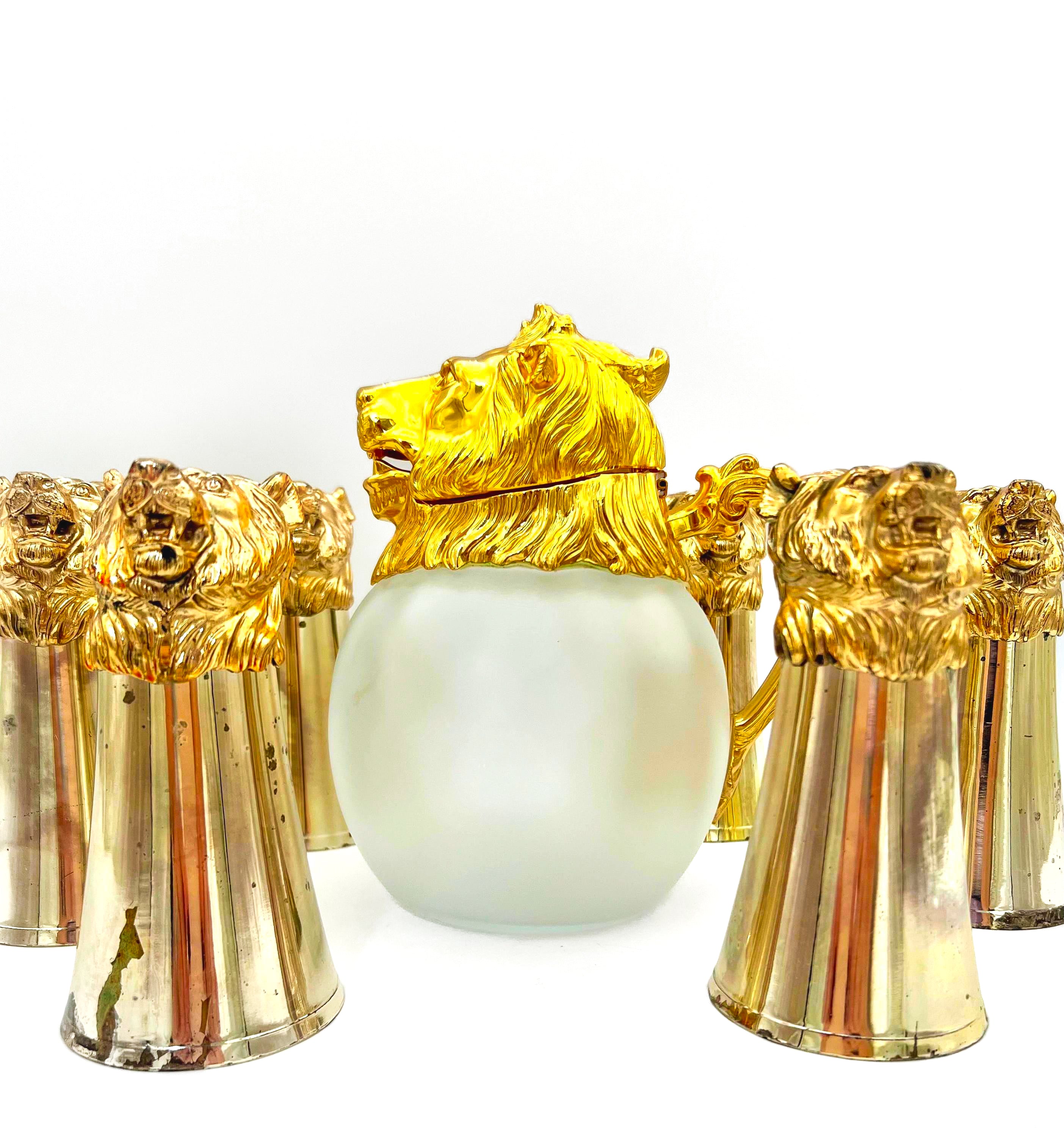Rare set of 7 Carole Stupell mid-century barware featuring a glass pitcher and stirrup cups with silver-toned lion head bases.