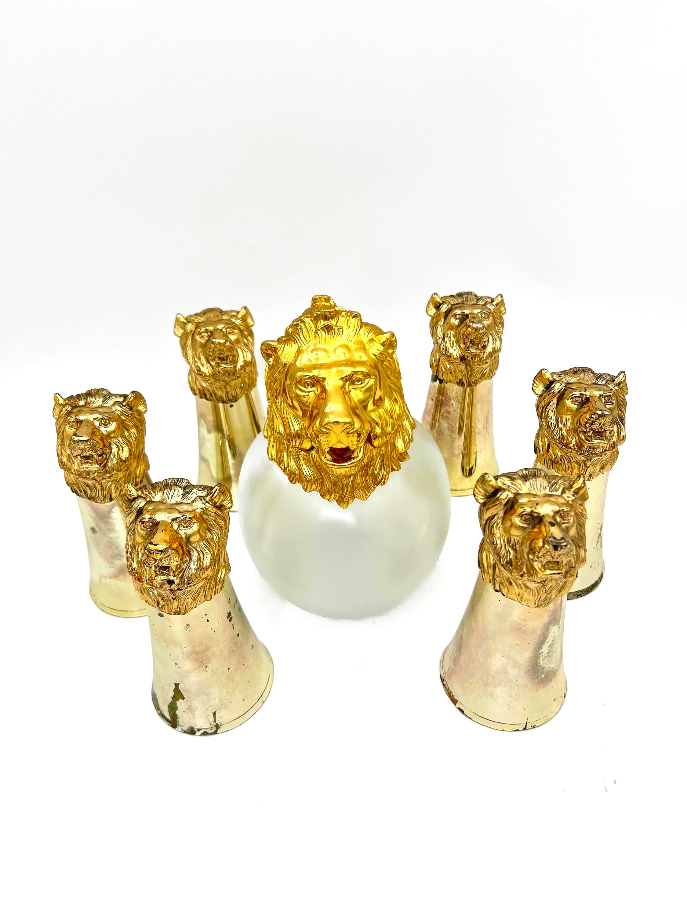 Rare set of 7 Carole Stupell mid-century barware featuring a glass pitcher and stirrup cups with silver-toned lion head bases.