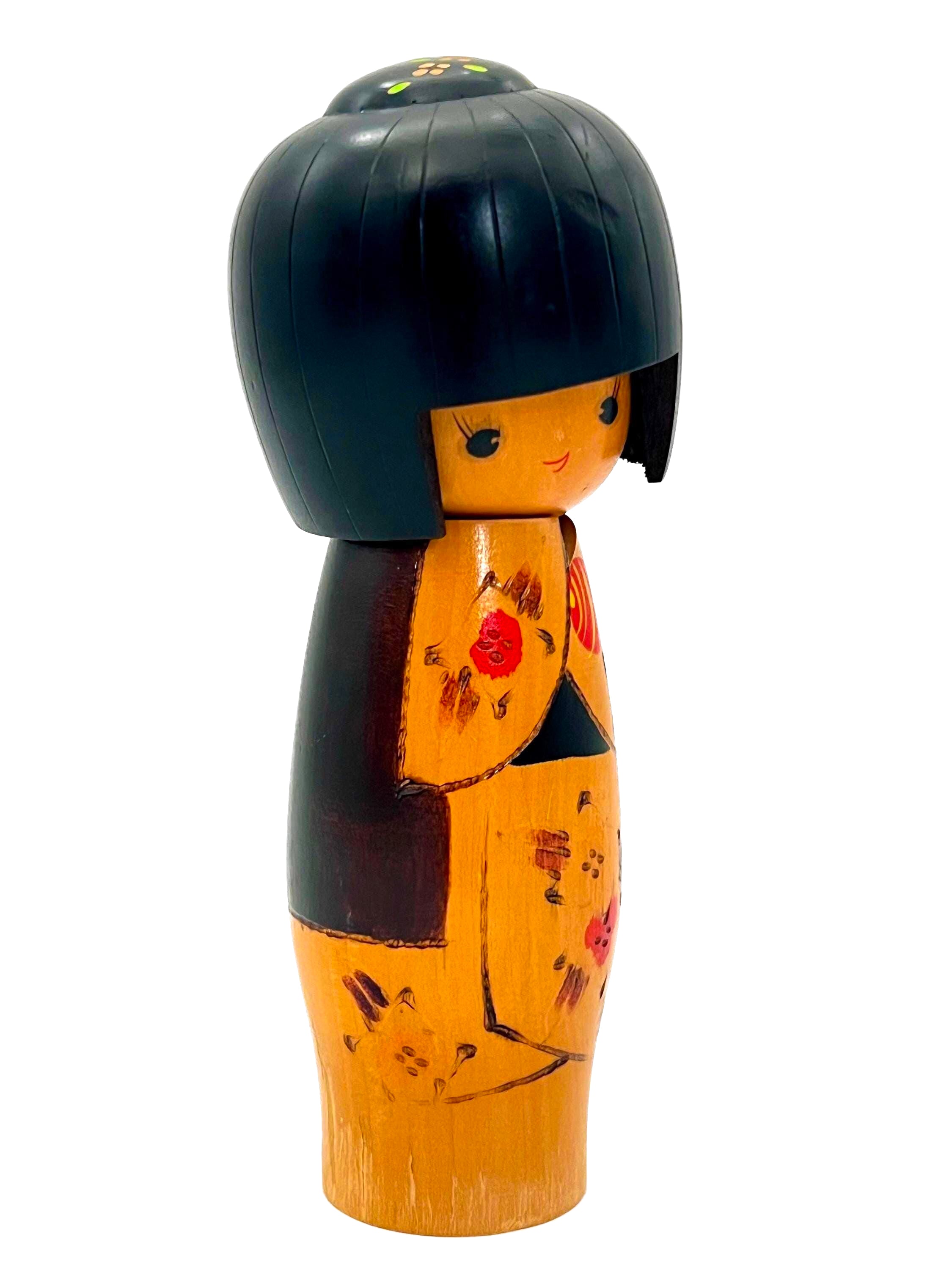Traditional vintage Japanese Kokeshi doll made of hand-painted wood with floral accents.